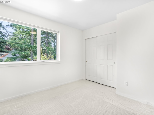 unfurnished bedroom featuring light carpet and a closet