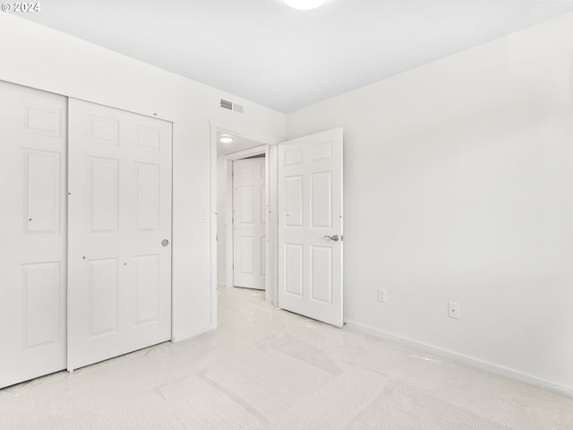 unfurnished bedroom featuring light carpet and a closet