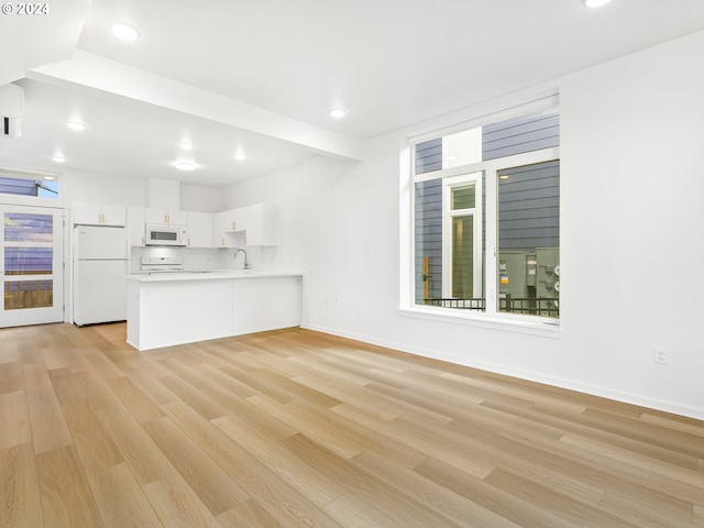 unfurnished living room with sink and light hardwood / wood-style floors