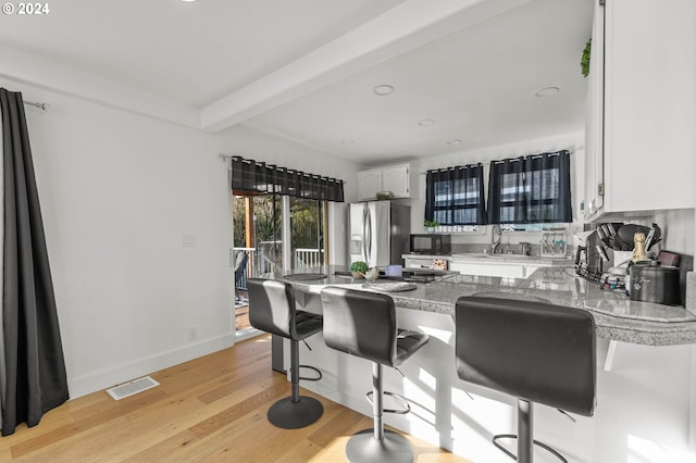 kitchen featuring light hardwood / wood-style floors, a kitchen breakfast bar, beamed ceiling, white cabinets, and stainless steel refrigerator with ice dispenser