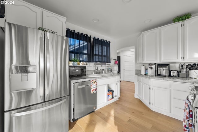 kitchen featuring white cabinets, appliances with stainless steel finishes, light hardwood / wood-style floors, and sink