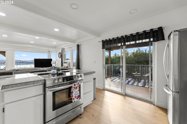 kitchen featuring stainless steel appliances, light wood-type flooring, beamed ceiling, and white cabinetry