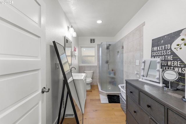 bathroom featuring tile walls, a shower with shower door, toilet, hardwood / wood-style flooring, and vanity with extensive cabinet space