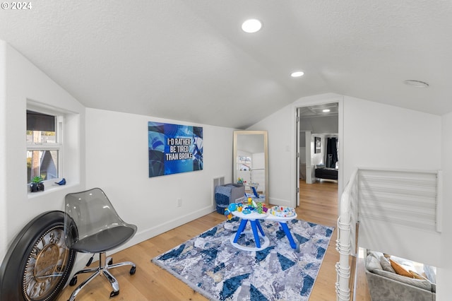 interior space featuring vaulted ceiling, light hardwood / wood-style floors, and a textured ceiling