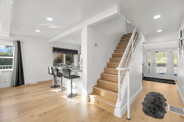 staircase featuring a healthy amount of sunlight and light hardwood / wood-style flooring