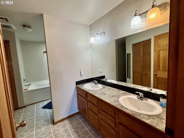 bathroom with tile patterned floors, vanity, and a bathing tub