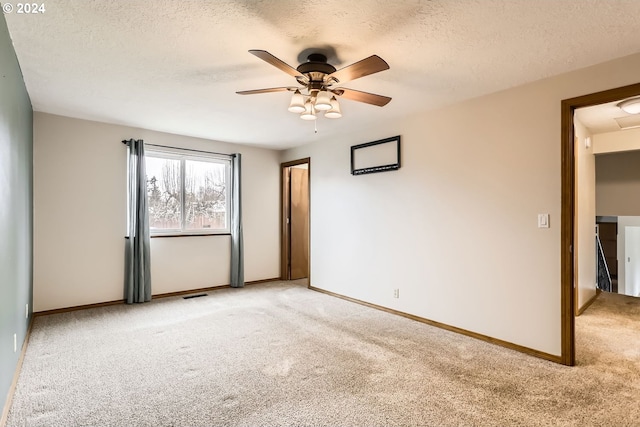 empty room with a textured ceiling, ceiling fan, and light carpet