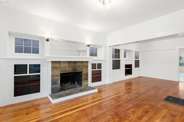 unfurnished living room with built in features and hardwood / wood-style flooring