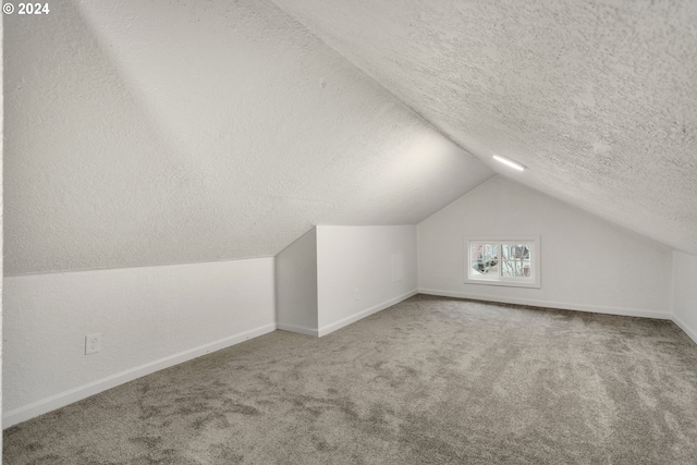 bonus room with a textured ceiling, vaulted ceiling, and carpet