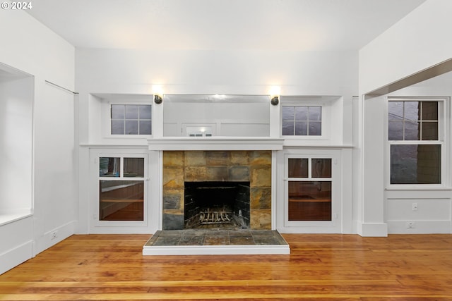 unfurnished living room with hardwood / wood-style floors and a tiled fireplace