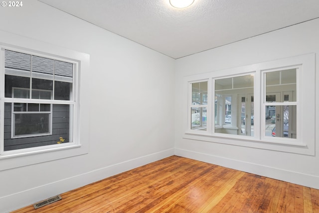 empty room with hardwood / wood-style floors and a textured ceiling