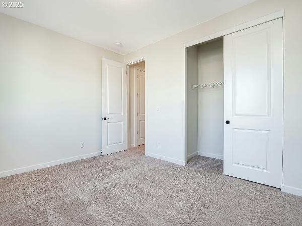 unfurnished bedroom featuring a closet, light colored carpet, and baseboards