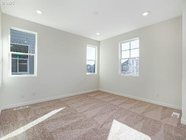 empty room featuring light carpet, recessed lighting, visible vents, and baseboards