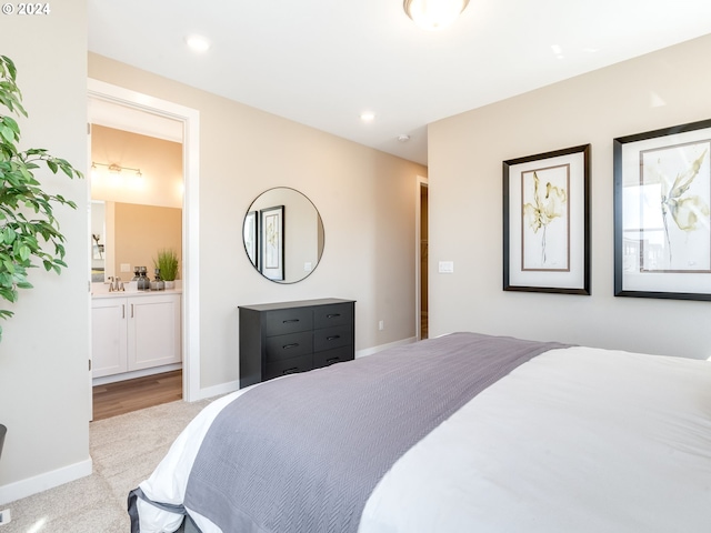 bedroom with light colored carpet, sink, and connected bathroom