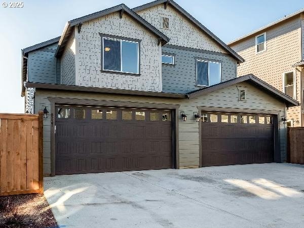 view of front facade with a garage, driveway, and fence