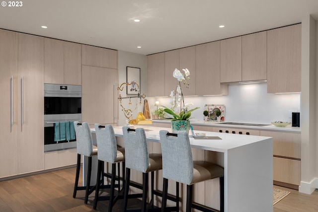 kitchen with a center island, a breakfast bar area, light countertops, stainless steel double oven, and modern cabinets