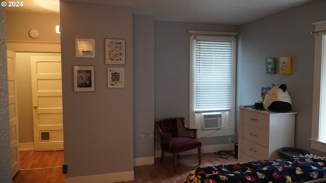 bedroom featuring multiple windows, hardwood / wood-style floors, and cooling unit