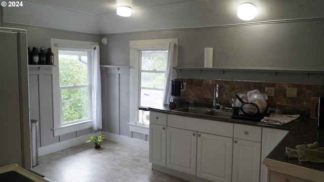 kitchen featuring lofted ceiling, sink, stainless steel refrigerator, tasteful backsplash, and white cabinets