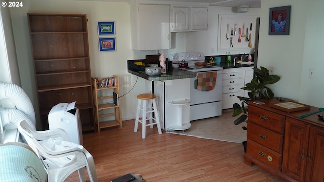 kitchen featuring electric stove, sink, light hardwood / wood-style floors, and white cabinets