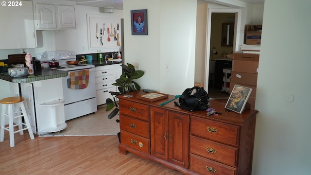 kitchen featuring white electric range oven, white cabinets, and light wood-type flooring