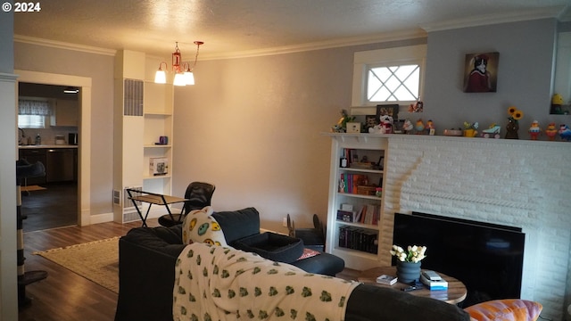 living room featuring an inviting chandelier, hardwood / wood-style floors, crown molding, and a fireplace