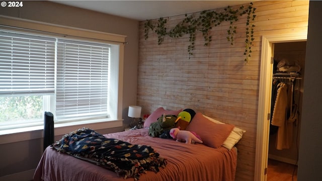 bedroom featuring a walk in closet, a closet, and wood walls