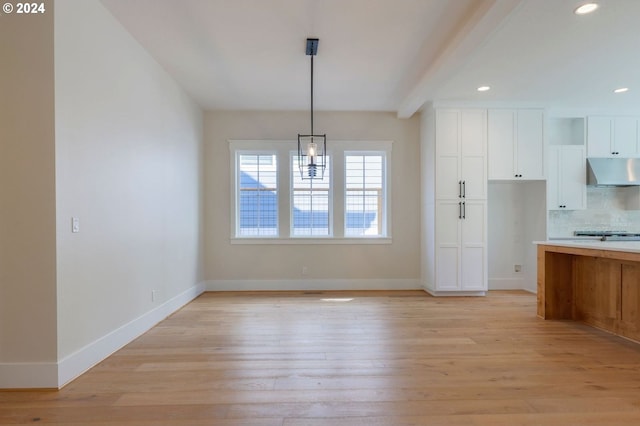 kitchen with backsplash, beam ceiling, decorative light fixtures, light hardwood / wood-style flooring, and white cabinetry