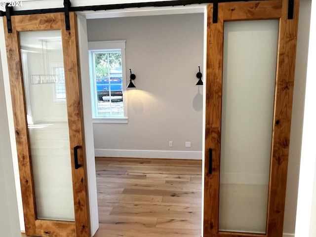 hall with a barn door and light hardwood / wood-style flooring