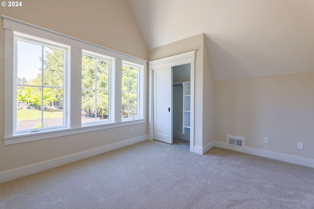 unfurnished bedroom with carpet, a closet, and vaulted ceiling