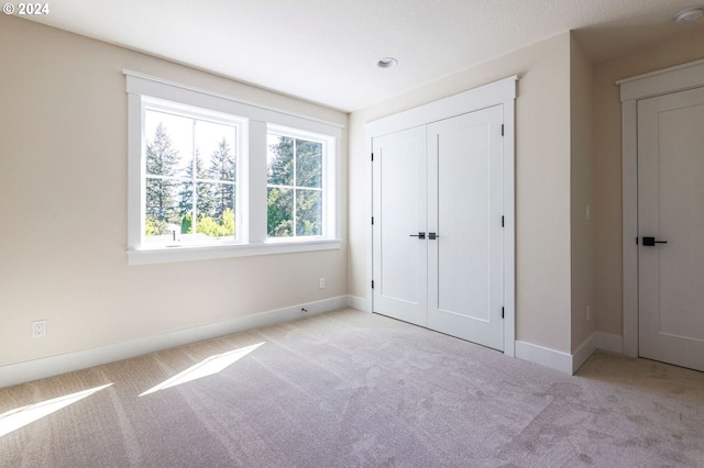 unfurnished bedroom featuring a closet and light colored carpet