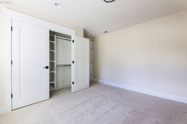 unfurnished bedroom featuring a closet and light colored carpet