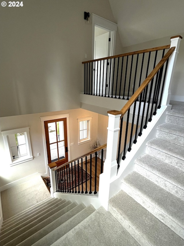 stairs featuring carpet flooring and high vaulted ceiling