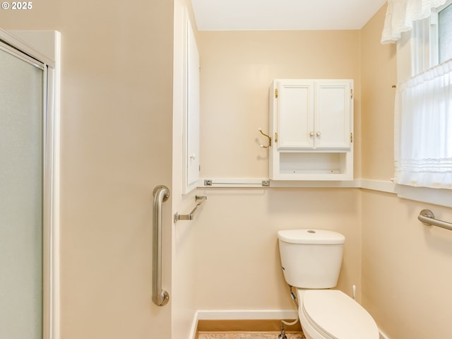 bathroom featuring toilet and a shower with door