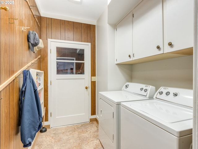 washroom featuring cabinets, wood walls, and independent washer and dryer