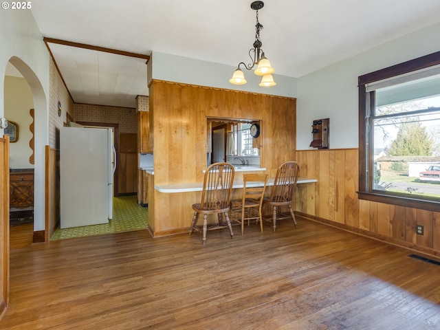 dining area featuring dark hardwood / wood-style flooring, wood walls, and a chandelier