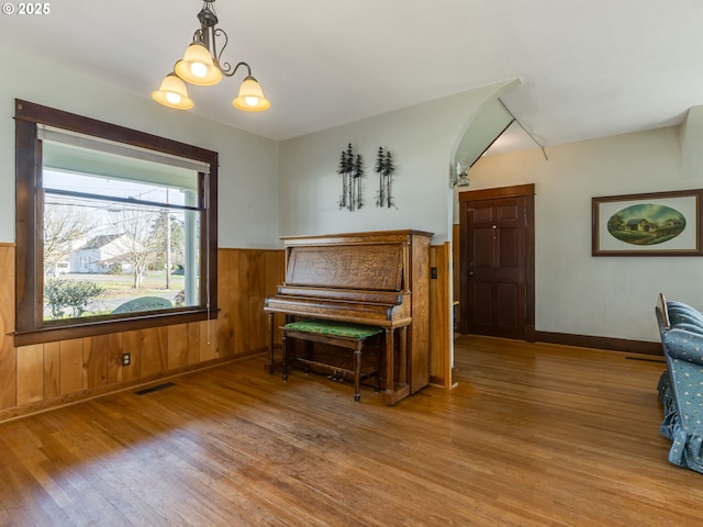 miscellaneous room with wood walls, a chandelier, and hardwood / wood-style flooring