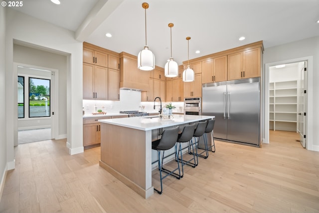 1669 NW Goodwin St, Camas, WA 98607 - kitchen with built in refrigerator, light wood finished floors, light countertops, a sink, and a breakfast bar