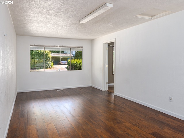 spare room featuring a textured ceiling and dark wood-type flooring