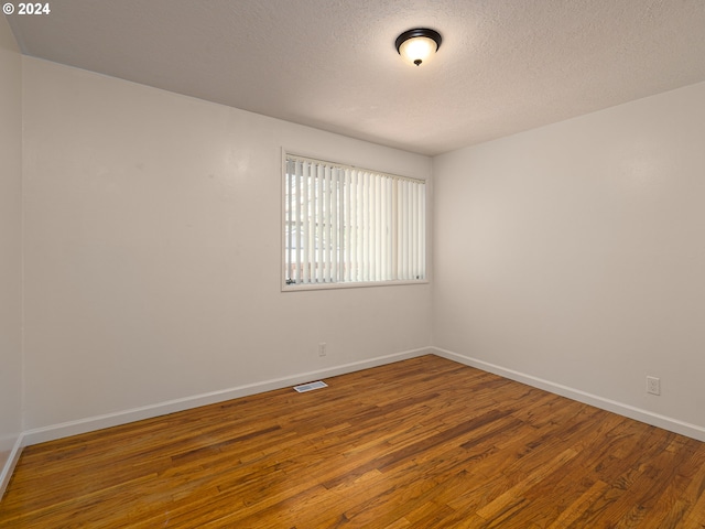 empty room with a textured ceiling and hardwood / wood-style floors