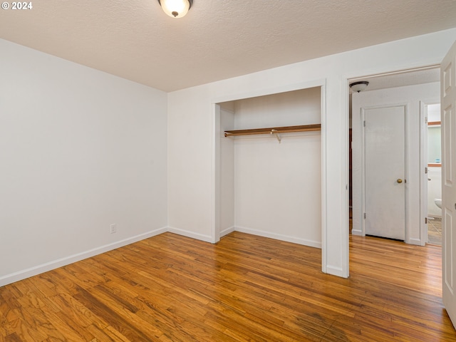 unfurnished bedroom featuring wood-type flooring, a textured ceiling, and a closet