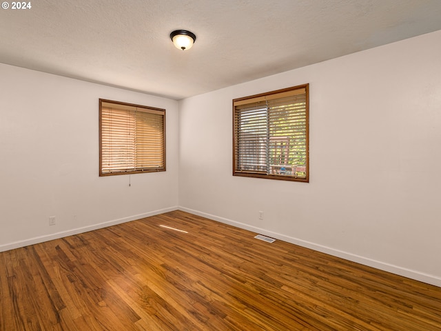 spare room featuring wood-type flooring and a textured ceiling