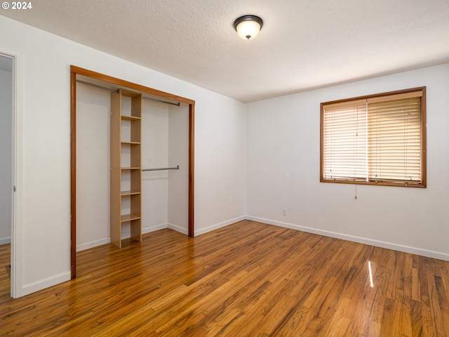 unfurnished bedroom with a textured ceiling, hardwood / wood-style floors, and a closet