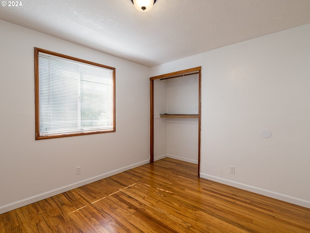 unfurnished bedroom with hardwood / wood-style flooring, a closet, and a textured ceiling