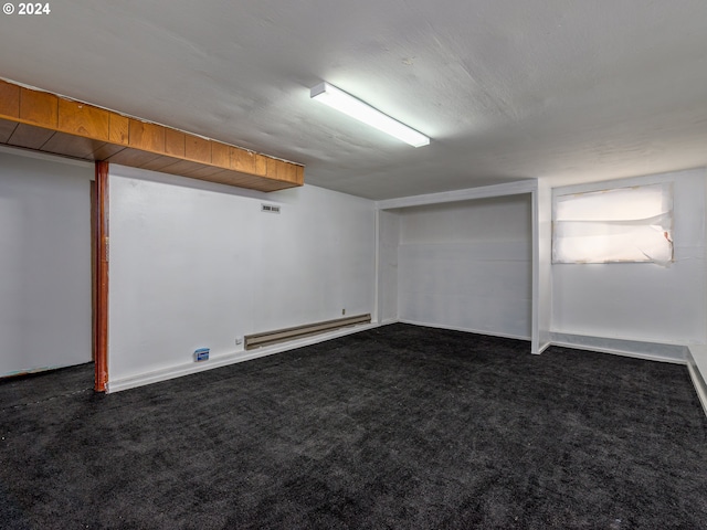 basement with dark colored carpet and a baseboard radiator