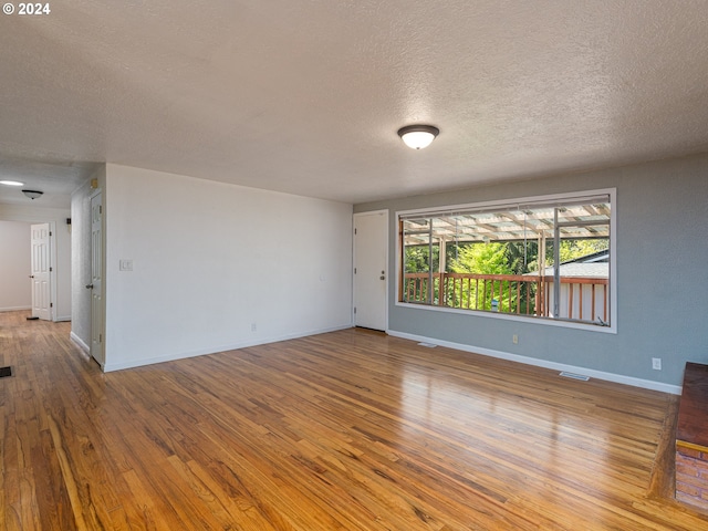 unfurnished room with wood-type flooring and a textured ceiling