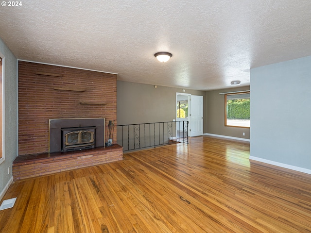 unfurnished living room featuring a brick fireplace, a textured ceiling, and hardwood / wood-style flooring