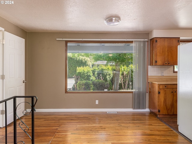 dining area with light wood-type flooring, a textured ceiling, and a wealth of natural light