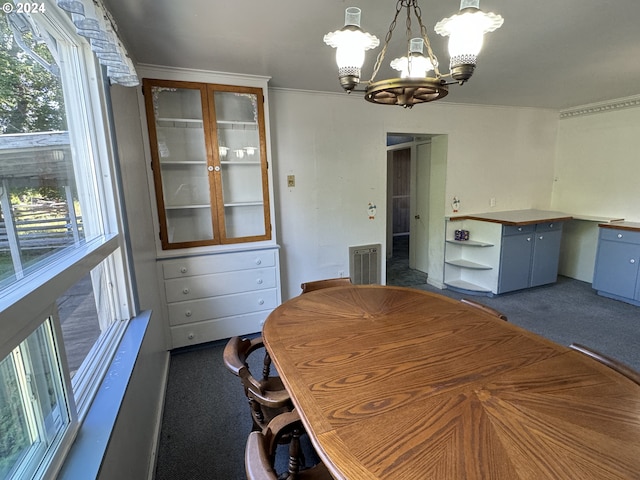 unfurnished dining area with visible vents, a chandelier, and dark colored carpet