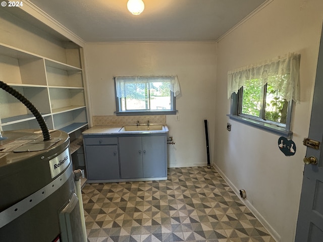 laundry area featuring a healthy amount of sunlight, cabinet space, a sink, and light floors