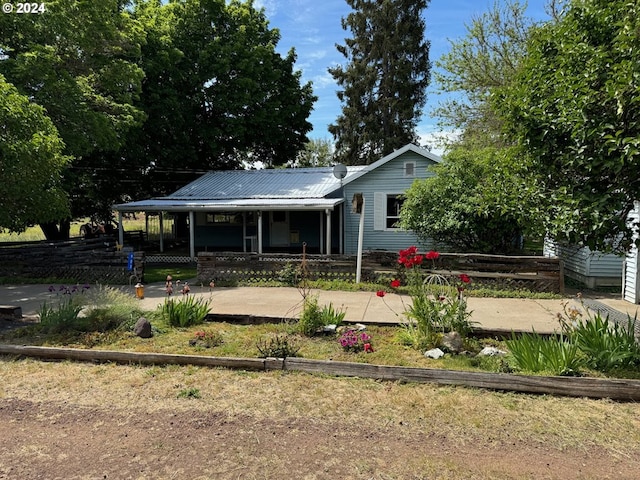 back of house featuring covered porch, metal roof, and a fenced front yard